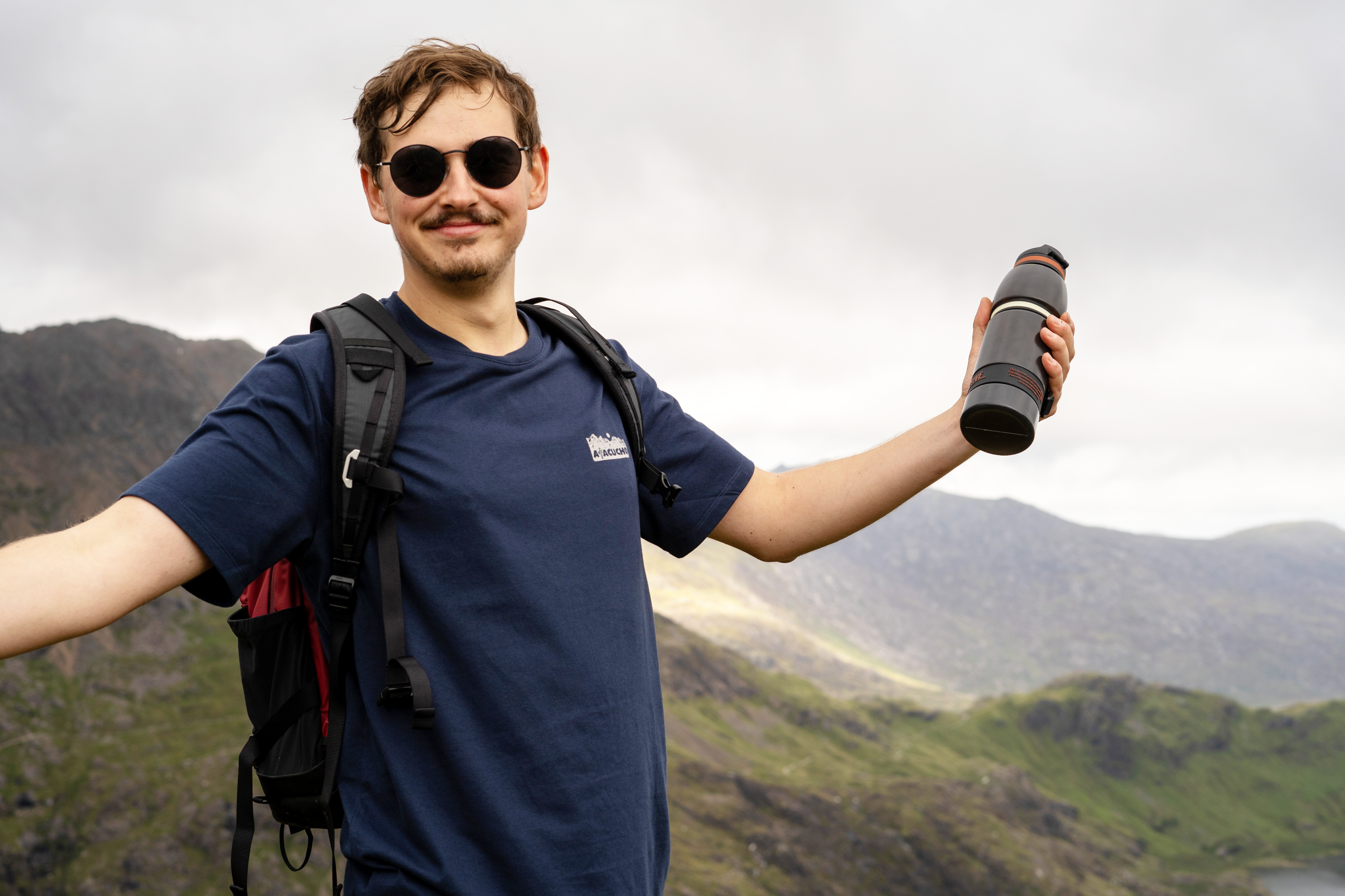 man in sunglassess out hiking and holding his custom water to go bottle
