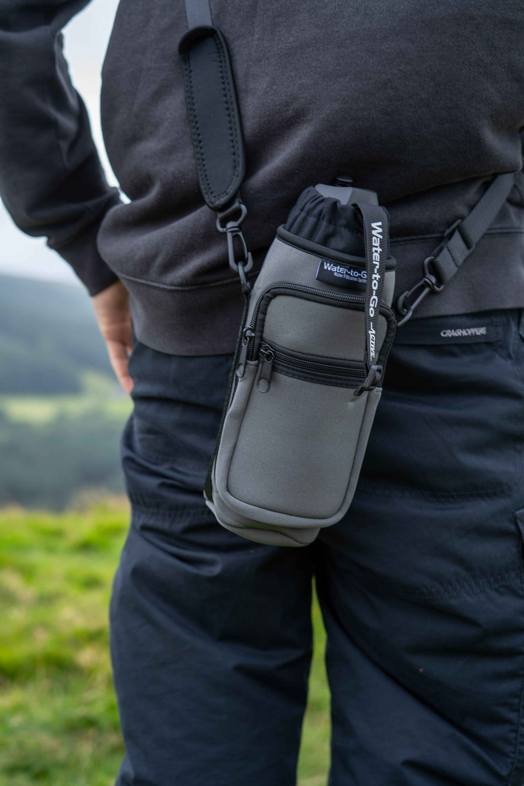 water to go insulated bottle carrier worn by a man in black clothing on a hill