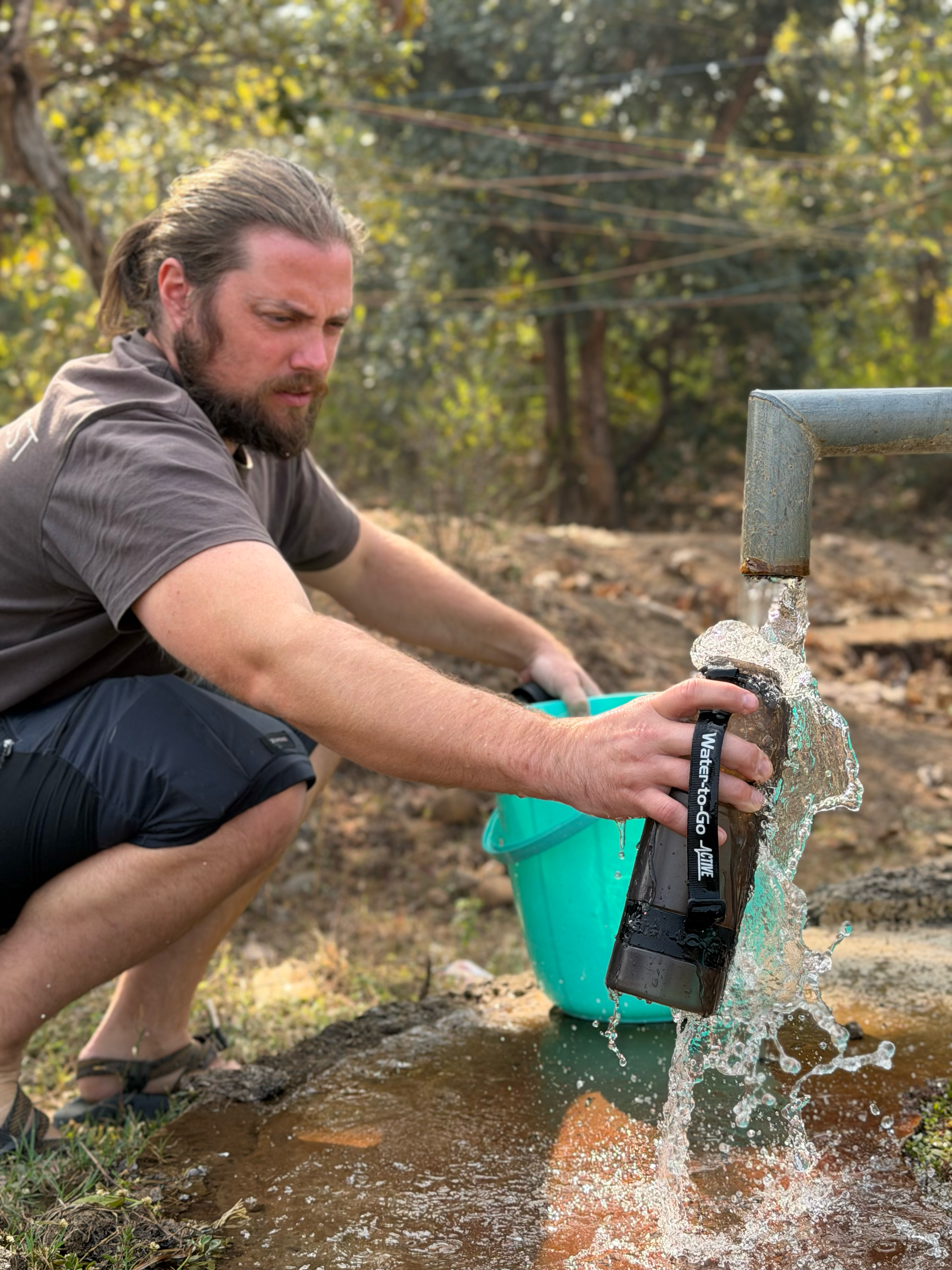 man filling up his 1 litre water to go filter bottle in jet back from a dirty pipe